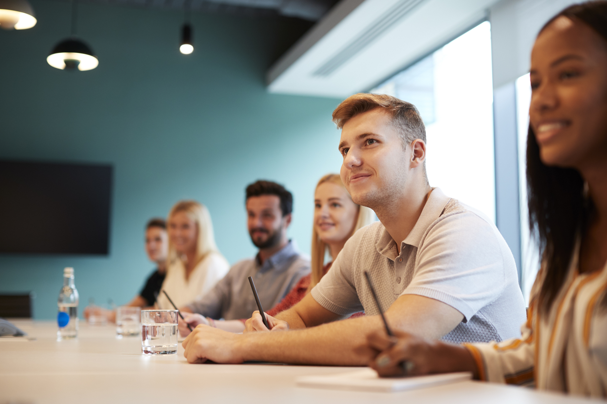 GettyImages-1051777582 Photo of a group of young interns sitting at a table in an office