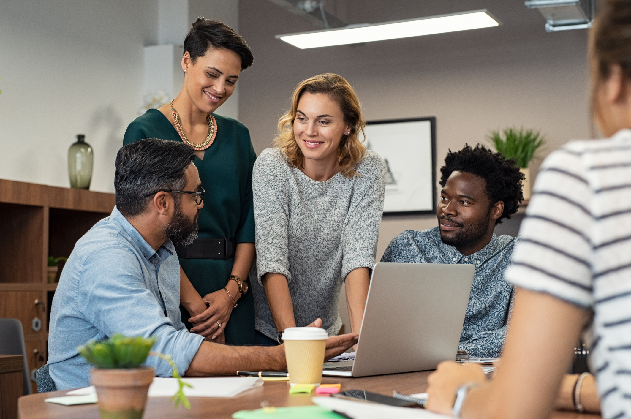 Photo of multiethnic business people talking and smiling during meeting in office. 