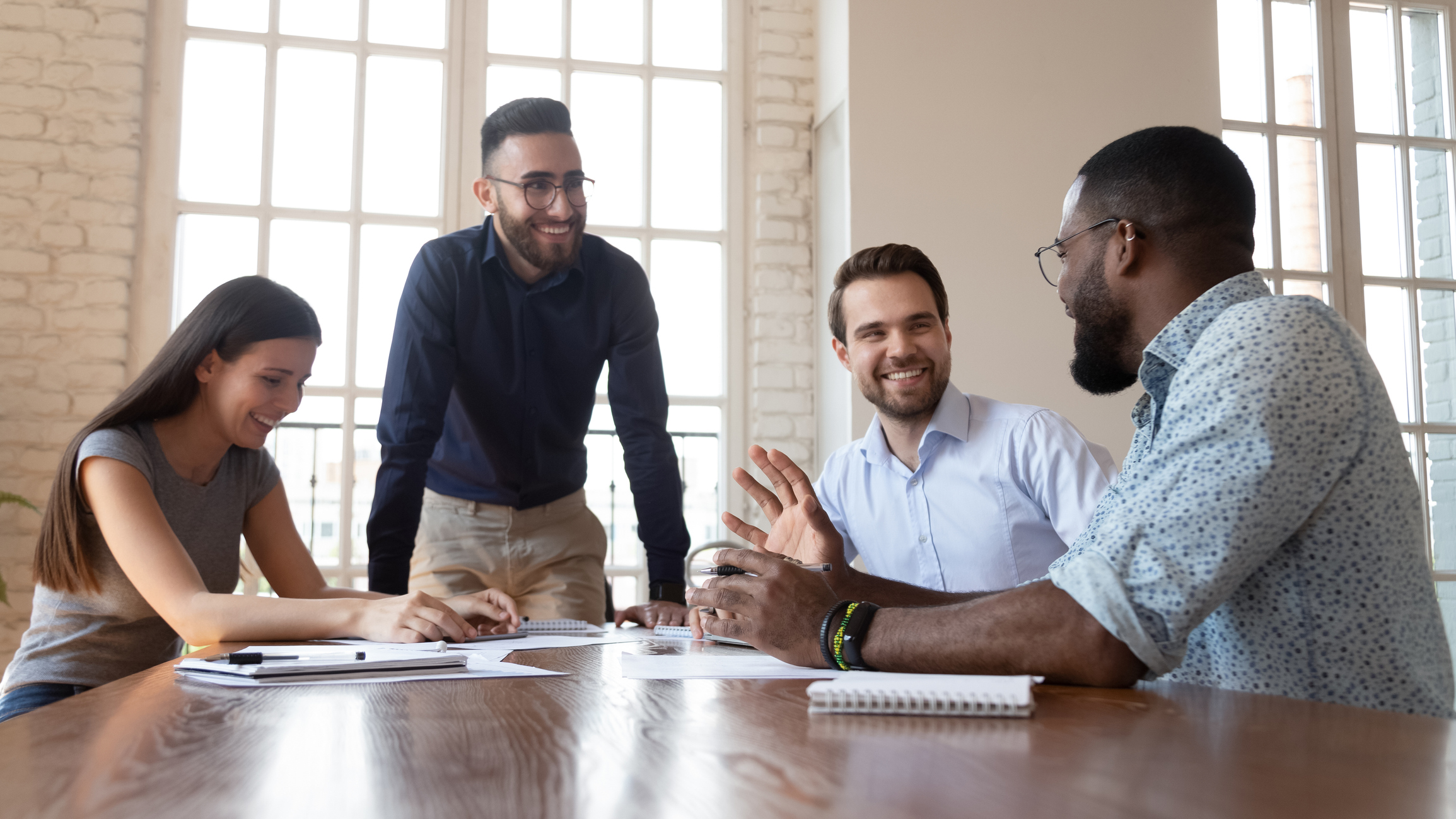 Photo of smiling team leader with colleagues listening around a table.