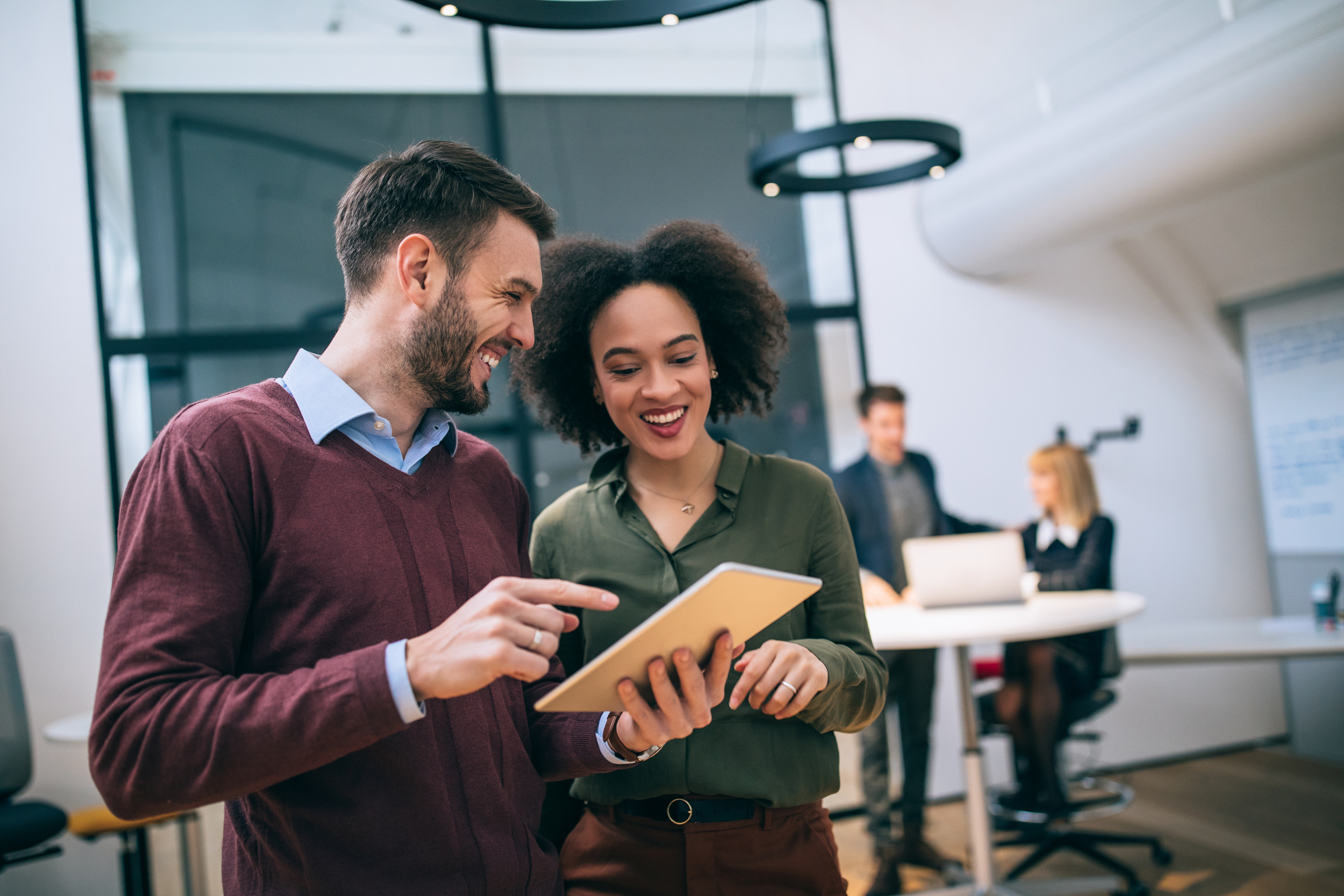 GettyImages-938875970 Photo of coworkers standing in an office, looking at a digital tablet