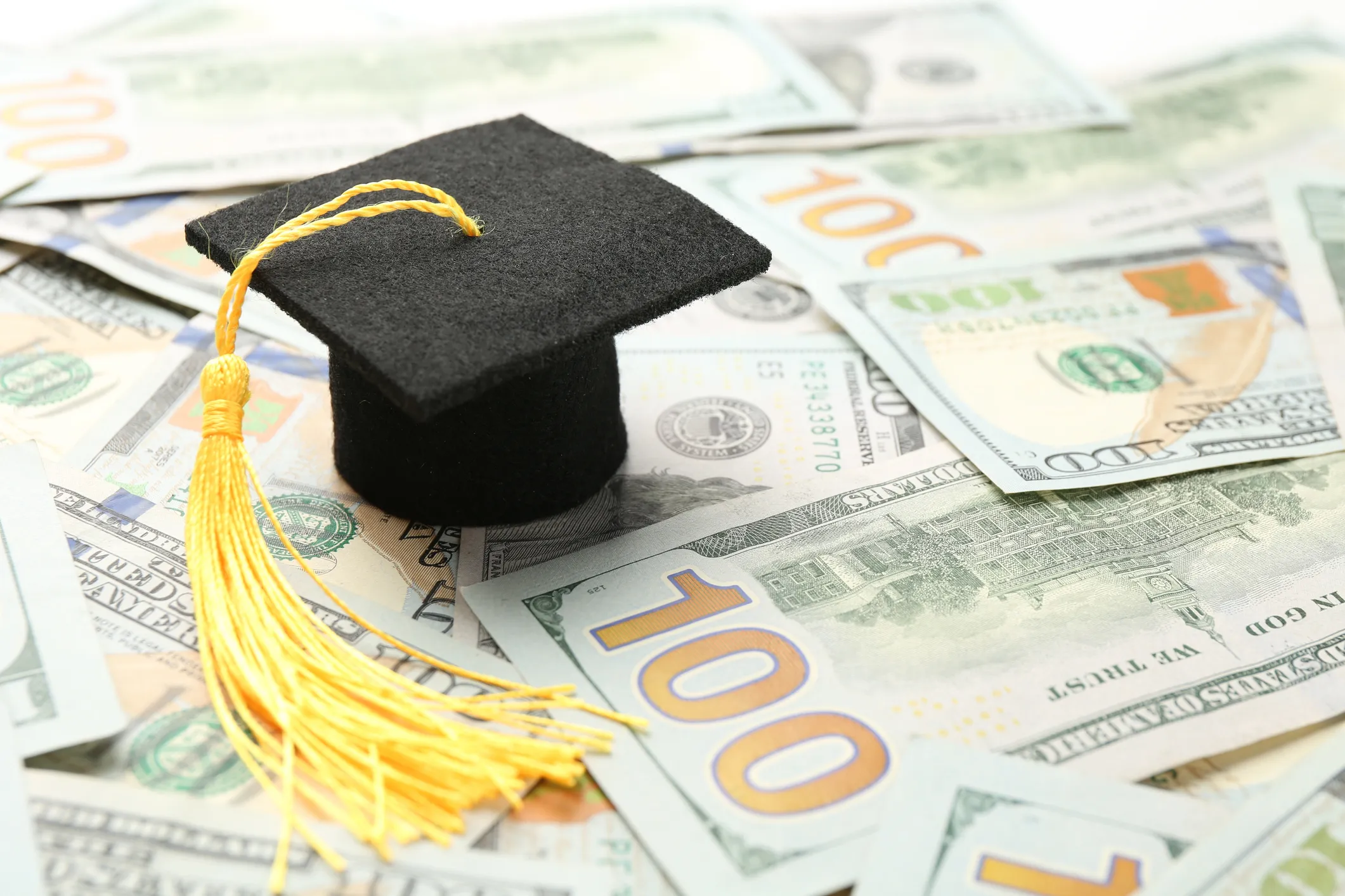 Image of a graduation cap on dollar bills